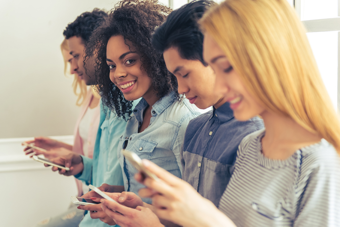 Young,People,Of,Different,Nationalities,Using,Smartphones,And,Smiling,While